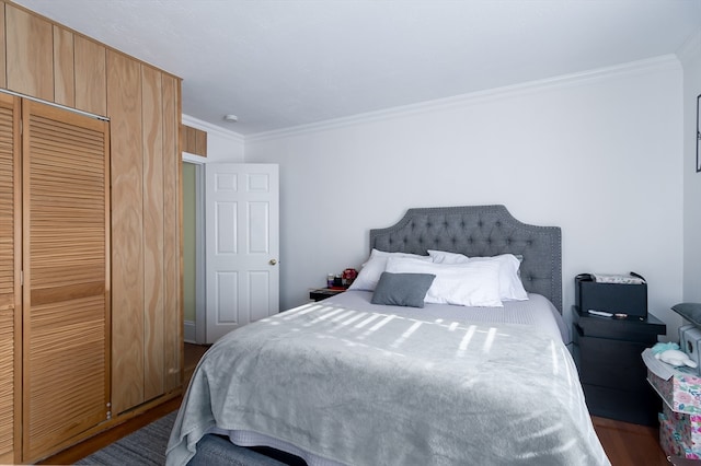 bedroom with hardwood / wood-style flooring, crown molding, and a closet