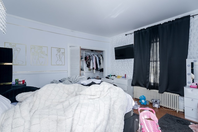 bedroom featuring ornamental molding, hardwood / wood-style floors, a closet, and radiator heating unit