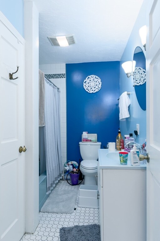 bathroom featuring curtained shower, tile patterned floors, vanity, and toilet