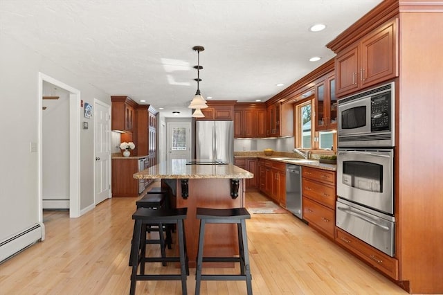 kitchen featuring a center island, a warming drawer, light wood finished floors, stainless steel appliances, and a baseboard heating unit