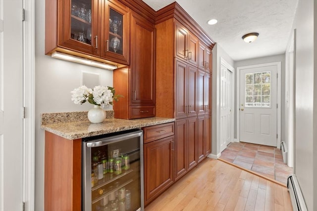 bar with beverage cooler, a baseboard heating unit, light wood-style flooring, and a textured ceiling