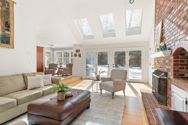 living room featuring high vaulted ceiling, a wealth of natural light, a brick fireplace, and light wood finished floors