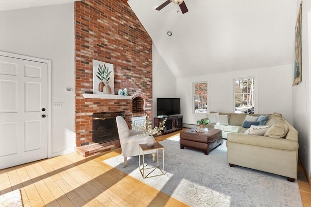 living area with a baseboard radiator, wood-type flooring, a brick fireplace, ceiling fan, and high vaulted ceiling