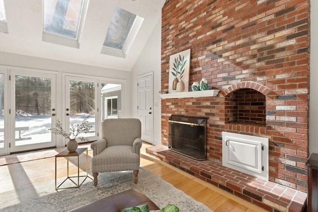 living room with high vaulted ceiling, a fireplace, and light wood-style flooring