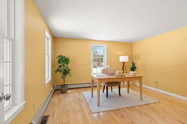 office space featuring visible vents, baseboards, a baseboard radiator, a textured ceiling, and light wood-type flooring