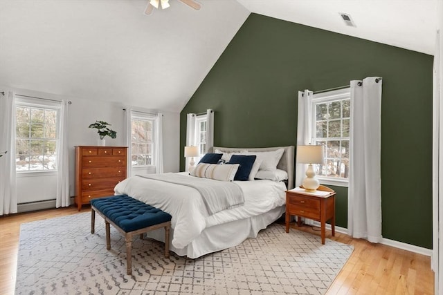 bedroom featuring lofted ceiling, multiple windows, and light wood-type flooring