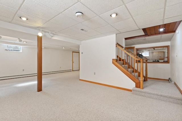 below grade area featuring rail lighting, baseboards, a drop ceiling, and carpet flooring