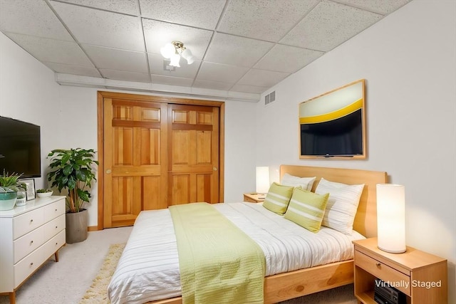 bedroom with a paneled ceiling, a closet, visible vents, and carpet flooring