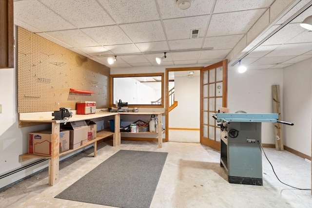 interior space with a baseboard heating unit, baseboards, and a drop ceiling