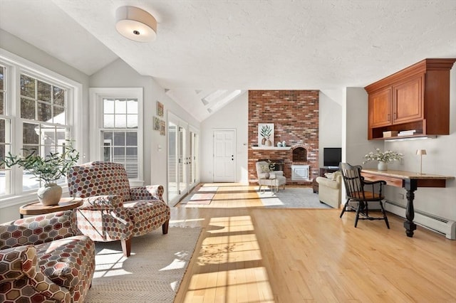 living area featuring a baseboard radiator, light wood-style floors, a brick fireplace, vaulted ceiling, and a textured ceiling