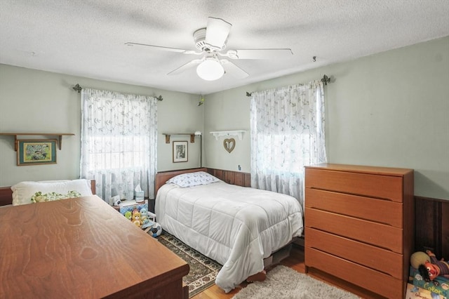 bedroom featuring ceiling fan, a textured ceiling, and light hardwood / wood-style flooring