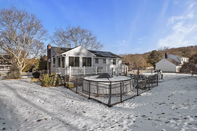 snow covered rear of property featuring solar panels