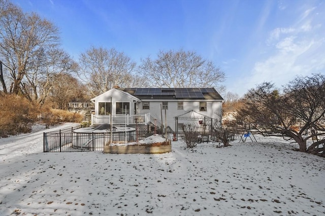 snow covered property featuring solar panels and a sunroom