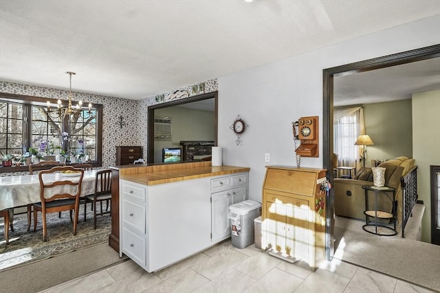 kitchen featuring hanging light fixtures, white cabinets, a notable chandelier, and wood counters