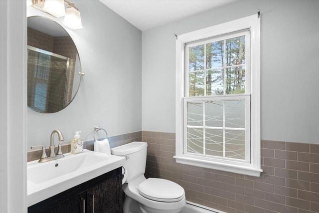 full bathroom featuring vanity, a wainscoted wall, a shower stall, tile walls, and toilet