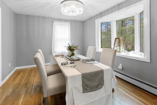 dining room with light wood-style floors, baseboards, a chandelier, and a baseboard radiator