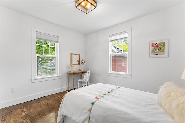 bedroom featuring multiple windows, baseboards, and wood finished floors