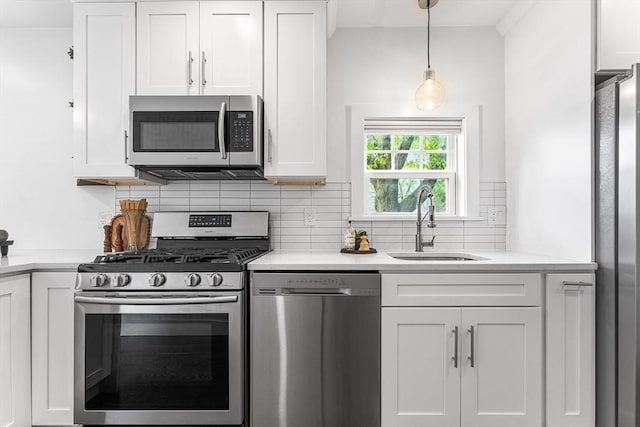 kitchen featuring appliances with stainless steel finishes, light countertops, white cabinets, decorative backsplash, and a sink