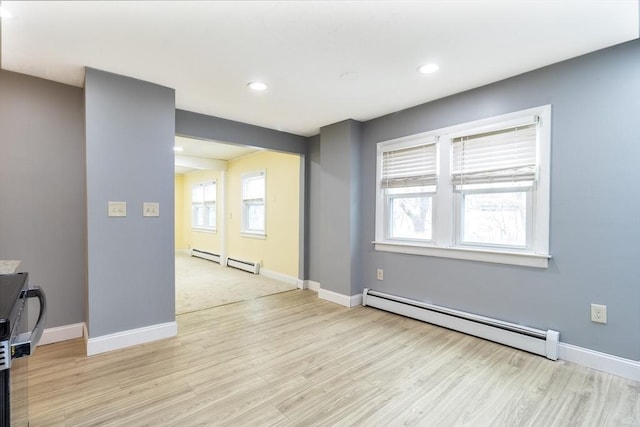 spare room with a baseboard heating unit and light hardwood / wood-style floors