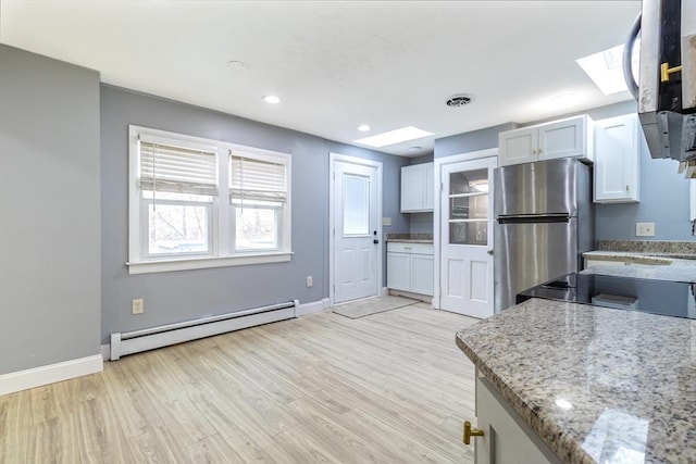 kitchen with stainless steel refrigerator, a baseboard radiator, light stone countertops, light hardwood / wood-style floors, and white cabinets