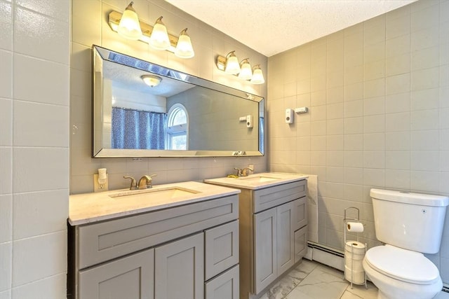 bathroom with vanity, toilet, tile walls, and a textured ceiling