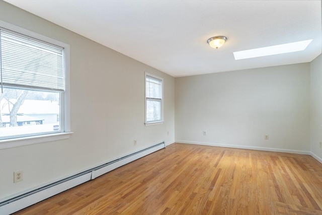 unfurnished room with a baseboard heating unit, light wood-type flooring, and a skylight