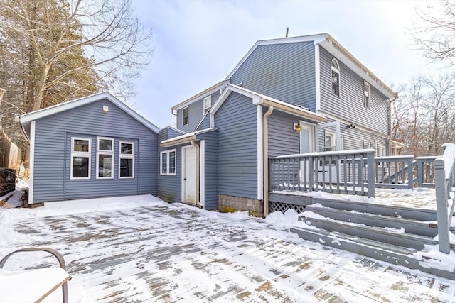 snow covered rear of property with a wooden deck