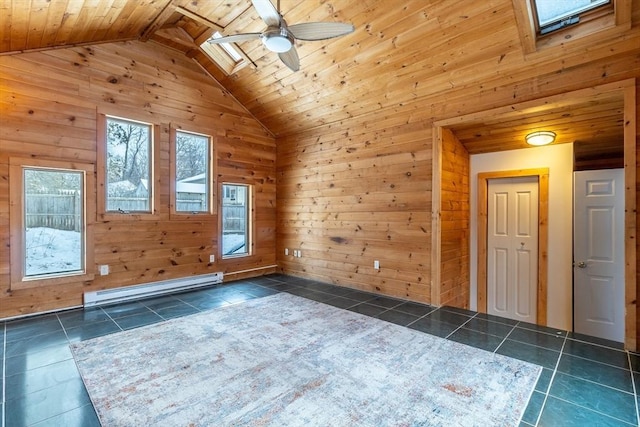 tiled empty room featuring vaulted ceiling with skylight, wood walls, a baseboard radiator, ceiling fan, and wood ceiling