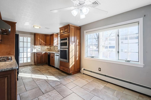 kitchen featuring backsplash, light stone counters, stainless steel appliances, ceiling fan, and a baseboard heating unit