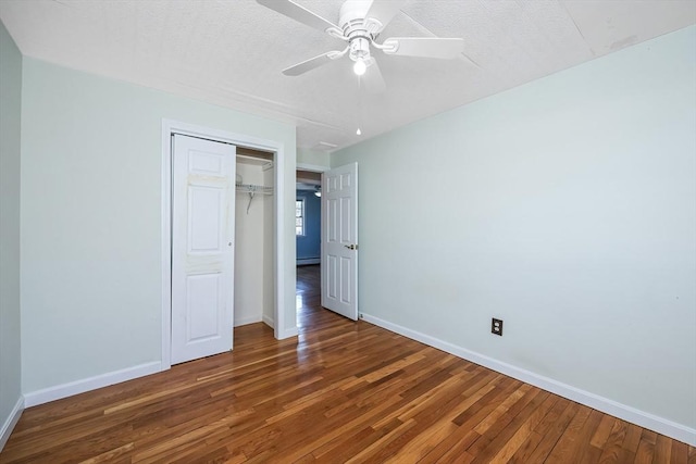 unfurnished bedroom with ceiling fan, dark wood-type flooring, a baseboard radiator, and a closet