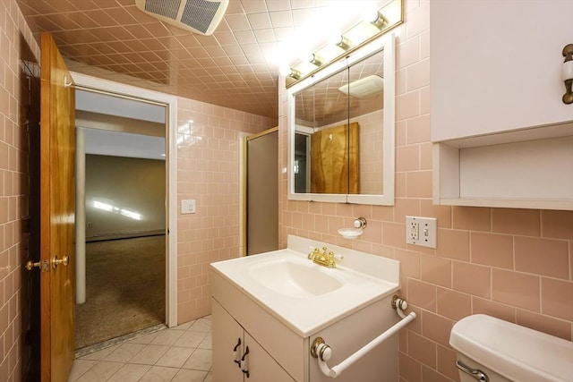 bathroom with tile patterned flooring, toilet, a shower with door, vanity, and tile walls