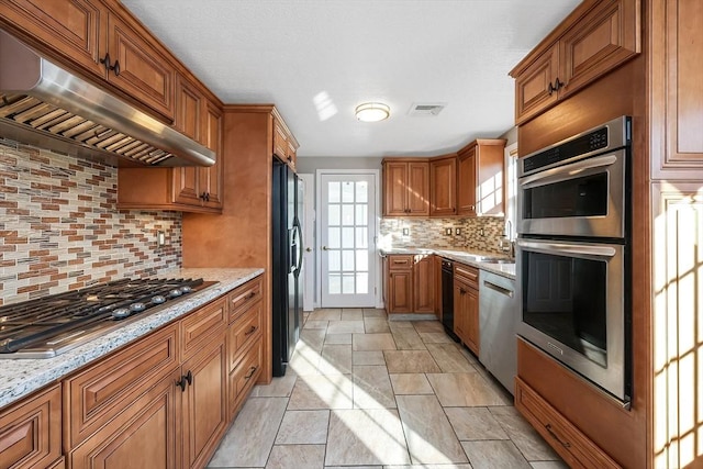 kitchen featuring tasteful backsplash, light stone counters, and black appliances