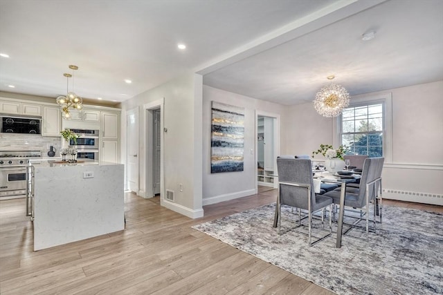 dining area with baseboard heating, light hardwood / wood-style flooring, and a notable chandelier