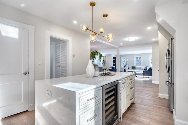 kitchen with light hardwood / wood-style flooring, wine cooler, light stone countertops, a kitchen island, and decorative light fixtures