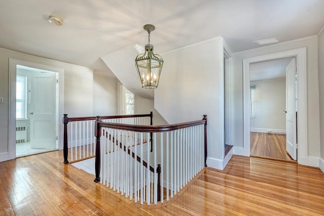 corridor with hardwood / wood-style flooring, ornamental molding, radiator, and a chandelier