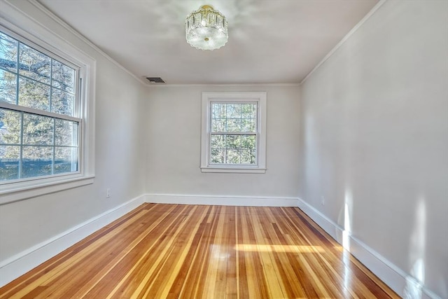 spare room with light hardwood / wood-style flooring, ornamental molding, and a healthy amount of sunlight