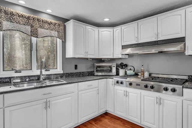 kitchen with dark stone counters, white cabinets, sink, wood-type flooring, and stainless steel gas cooktop