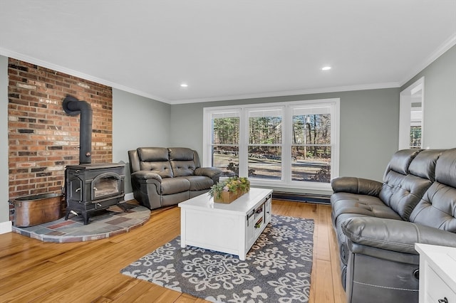 living room featuring light wood-type flooring, ornamental molding, and a wood stove