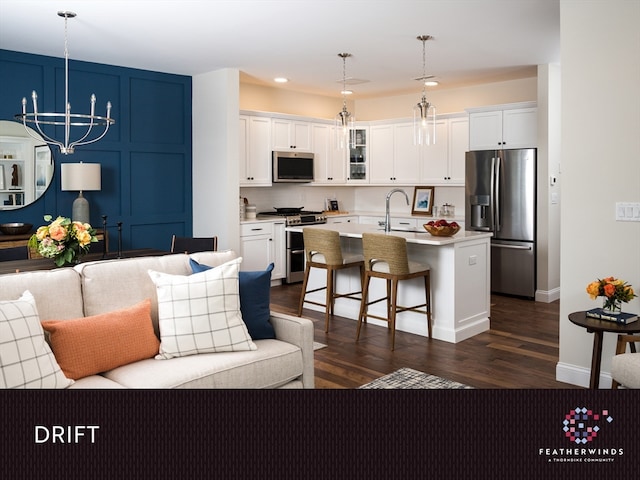 kitchen with a center island with sink, stainless steel appliances, and white cabinetry