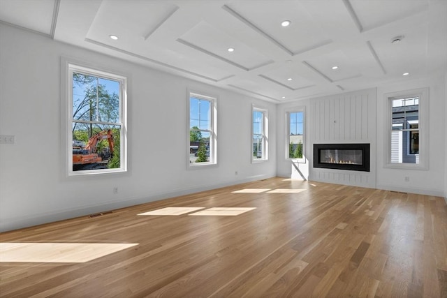 unfurnished living room with coffered ceiling, plenty of natural light, wood finished floors, a large fireplace, and recessed lighting