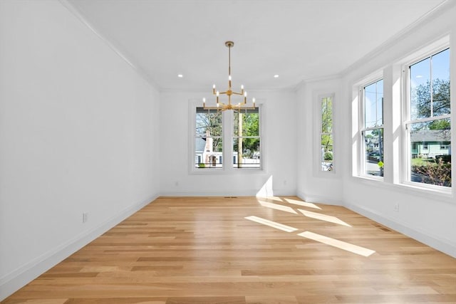 unfurnished dining area featuring a chandelier, crown molding, light wood finished floors, baseboards, and recessed lighting