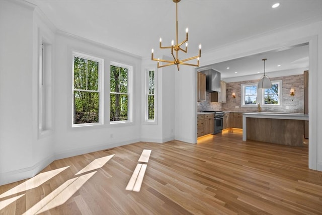 unfurnished dining area featuring a chandelier, light wood finished floors, recessed lighting, baseboards, and crown molding
