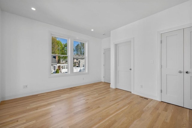unfurnished bedroom with light wood-style floors, baseboards, recessed lighting, and multiple closets