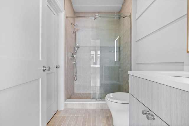 bathroom featuring a stall shower, toilet, and vanity
