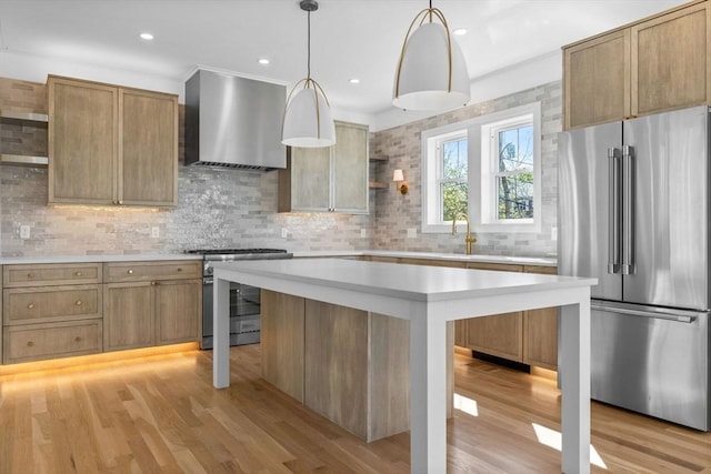 kitchen featuring high end appliances, wall chimney exhaust hood, light countertops, light wood-type flooring, and decorative backsplash