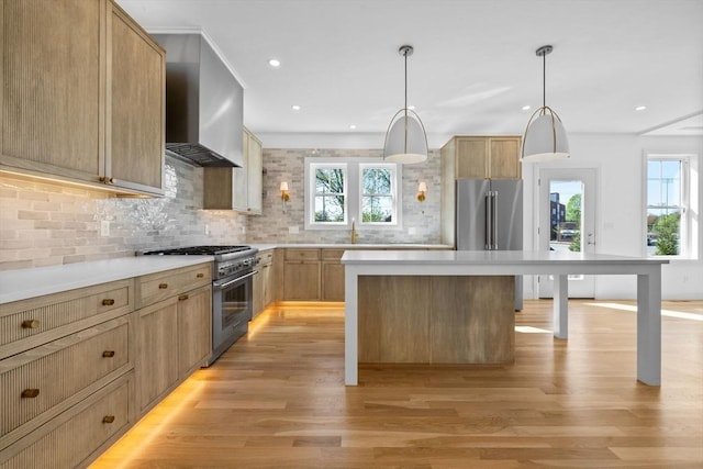 kitchen with high quality appliances, light wood finished floors, wall chimney range hood, tasteful backsplash, and recessed lighting