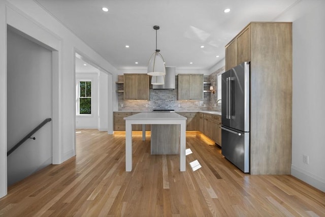 kitchen featuring high end fridge, open shelves, wall chimney range hood, light countertops, and tasteful backsplash