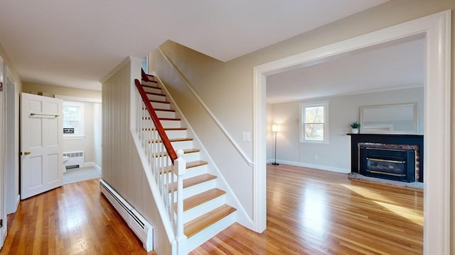 stairs with radiator, baseboard heating, and wood-type flooring