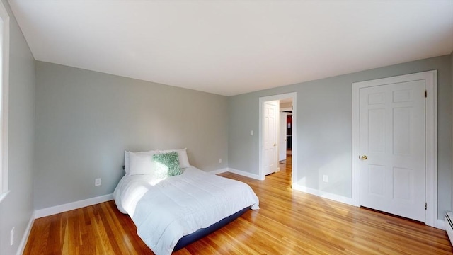 bedroom featuring hardwood / wood-style flooring, a closet, and a baseboard heating unit