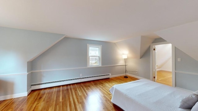 unfurnished bedroom with a baseboard heating unit, vaulted ceiling, and hardwood / wood-style floors